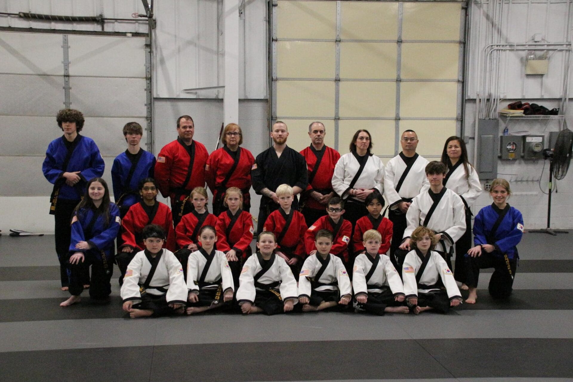 a group of people, both children and adults, dressed in karate uniforms and posing for a picture